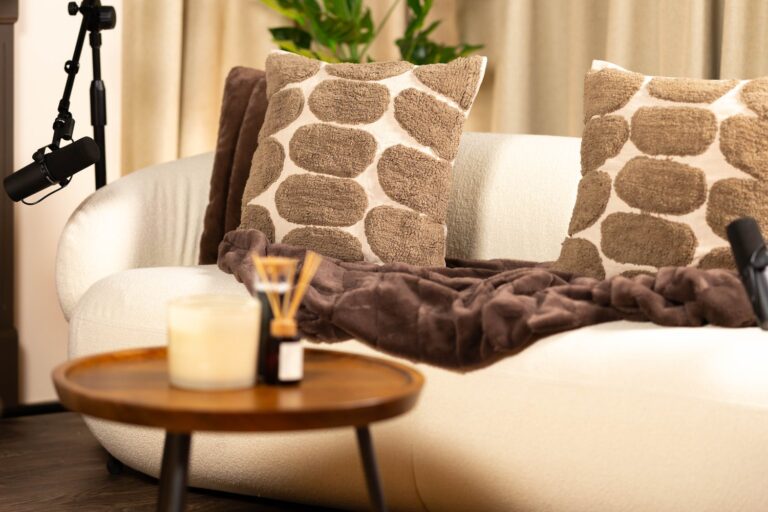The Creative Pod, boucle sofa with a throw and textured cushions beside a table with a candle and a broadcast microphone